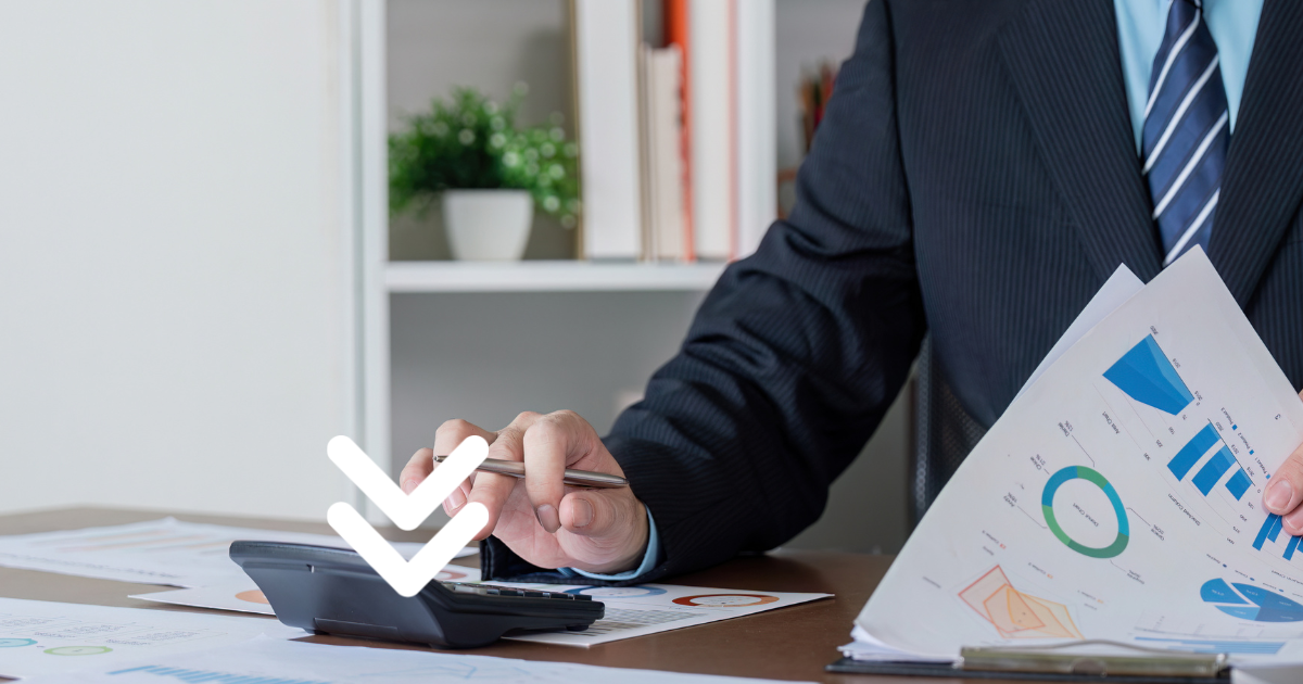 Manager reviewing reports with pen and calculator
